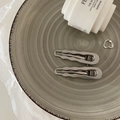 Dettaglio di fermagli per capelli ondulati argentati e anello a cuore su vassoio - Onda