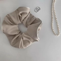 Macro detail of champagne satin scrunchie with white piped edges and smooth silk texture - Beige Apricot