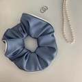 Detailed texture of blue satin scrunchie with cream piping and elegant pleats - Blue