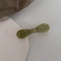 Detail view of olive green marble pattern bow hair clip with high gloss finish texture - Clear Green