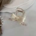 Détail d'une pince à cheveux avec nœud crème en acrylique et ressort métallique - Blanc