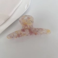 Close-up of acetate hair claw with pink yellow marble texture and golden text - Yellow Pink