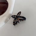 Macro shot of tortoise shell acetate bow hair claw with hollowed design and smooth finish - Deep Blue Coffee