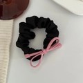 Detail of a black satin hair scrunchie featuring a modern pink metal bow ornament - Pink