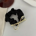 Detail of black satin scrunchie with a gold metal bow charm on a clean background - Gold