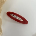 Glossy red oval resin barrette with gold French lettering on a white background - Red