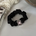 Detailed shot of black satin scrunchie with pink square gemstone and silver metal base - Gold Square Zircon