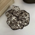 Detailaufnahme eines Satin-Haargummis mit Paisley-Muster und schwarzer Paspelierung - Kaffee Paisley