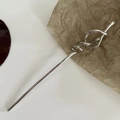 Dettaglio di un fermaglio per capelli in metallo argento con nodo a spirale su carta - Argento