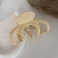Primo piano di una grande pinza per capelli in acrilico crema con finitura lucida su vassoio - Beige