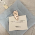 Elegant rose gold hair clip with wavy texture on a beige card over blue fabric - Water Drop Style / Pearlescent Pink