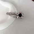 Detailopname van een zilveren bloem haarclip met zwart hart op een wit bord - Haarclip / Zilveren Bloemen Haarclip