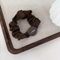 Detail of dark coffee satin scrunchie with Lucky engraved gold buckle on gray linen - Coffee-Round