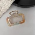 Detail view of square marble acetate hair claw clip with golden metal frame and spring - Iridescent Orange
