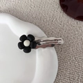 Dettaglio di un fermaglio per capelli a fiore nero su piatto di ceramica bianca e maglia - Fermaglio Fiore Nero