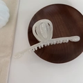 Close-up of elegant cream white tulip-shaped hair claw clip on a rustic wooden tray - White