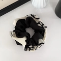 Détail d'un chouchou en satin multicouche avec motif à l'encre noir et blanc et texture soyeuse - Graffiti noir et blanc