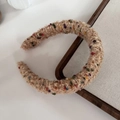 Close-up of khaki boucle knit headband with colorful dots and metallic thread detail - Brown