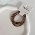 Detailed macro view of bronze elastic hair bands with golden beads on a white tray - Khaki