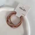 Close-up of pink elastic hair bands with gold metal cylinders on white ceramic tray - Korean Pink