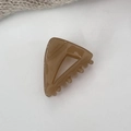 Detalle de la pinza triangular de ámbar con grabado dorado sobre fondo blanco - Café con Leche