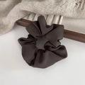 Close-up of brown pleated fabric scrunchie with twill texture on a wooden tray - Premium Grey