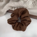 Detailed close-up of brown scrunchie on a wooden tray with elegant pleated fabric texture - Brown