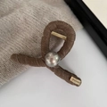Close-up of pearl hair claw clip with wool wrap texture and golden brand plate - Coffee