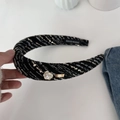 Detail showing tweed texture and camellia flower on a padded headband for women - Black