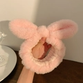 Dettaglio della fascia in peluche rosa con orecchie di coniglio e fiocco morbido - Rosa