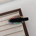Close-up of a colorful hand-woven yarn crochet hair clip on a wooden display stand - Black