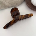 Close-up of tortoise shell hair claw clip with golden Barrette La France logo detail - Brown Stripes