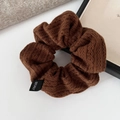 Detailed macro view of coffee-colored knitted scrunchie with cable texture and fabric label - Coffee
