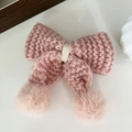 Détail d'une pince à cheveux nœud rose en tricot avec pompons doux et accent crème élégant - Rose