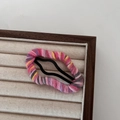 Detail of colorful wool-wrapped metal snap hair clips on a beige display tray - Pink