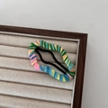 Primer plano de una horquilla de nube de lana colorida en un soporte de madera - Amarillo Verde Naranja