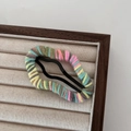 Detalle de horquilla de nube envuelta en hilo colorido sobre bandeja de joyería fina - Rosa Gris Verde