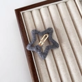 Barrette étoile tricotée grise avec clip en métal doré sur un plateau d'exposition - Gris