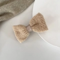 Detailed close-up of khaki knitted bow hair clip with satin ribbon on a white background - Beige