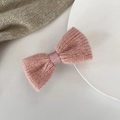 Detail shot of a soft pink knitted bow hair clip featuring fine hand-woven wool texture - Pink