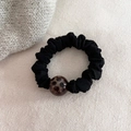 Dettaglio di un elastico per capelli in raso nero con una perla leopardata elegante - Perla Tonda Nera