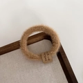 Close-up of soft plush coffee hair tie with fabric label on a rustic wooden tray - Khaki