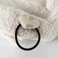Detalle de una cuenta de corazón de acetato blanco en una goma elástica negra para pelo - Blanco