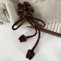 Dettaglio dello scrunchie in velluto marrone scuro con nastri lunghi e ciondoli a tulipano - Marrone