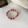 Detail van kleurrijke pluche gevlochten haarelastiek met harskraal op handdoek - Oranje Blauw