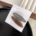 Set of two oval hair clips in muted green and marble amber on a display card - Brown