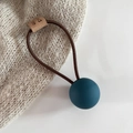 Detailed close-up of matte dark teal ball and elastic hair tie with leather label - Blue