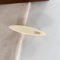Close-up of cream oval resin hair clip with gold metal clamp and handmade engraving - Off-white