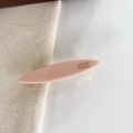 Close-up of pink oval resin hair clip with gold SANSHINE Handmade logo on fabric - Pink