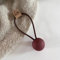 Close-up of brown elastic hair tie featuring matte burgundy ball and cute bear leather tag - Burgundy